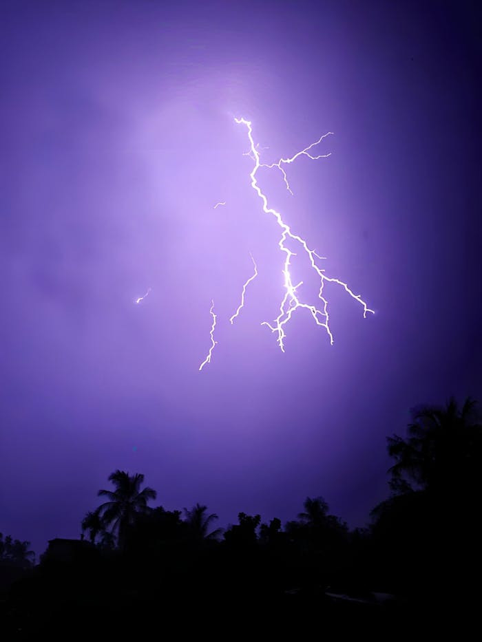 A vibrant purple-hued sky explodes with a powerful lightning strike.